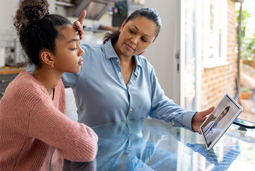 Mother and daughter looking at tablet during a virtual doctor appointment