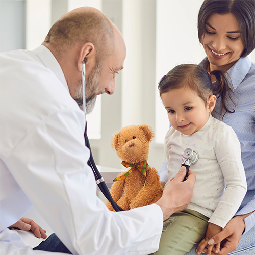 Doctor providing wellness exam on child that is sitting on mothers lap