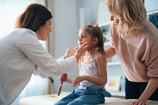 doctor providing wellness exam on child with mother looking on