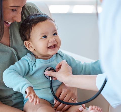 Doctor using stethoscope on smiling baby during exam