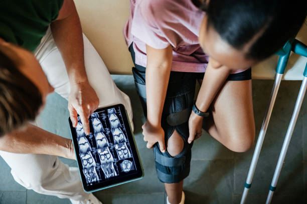 patient with knee injury looks at x-ray results with physician