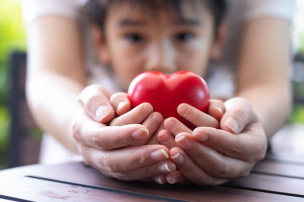 Person and child holding a red heart in hands