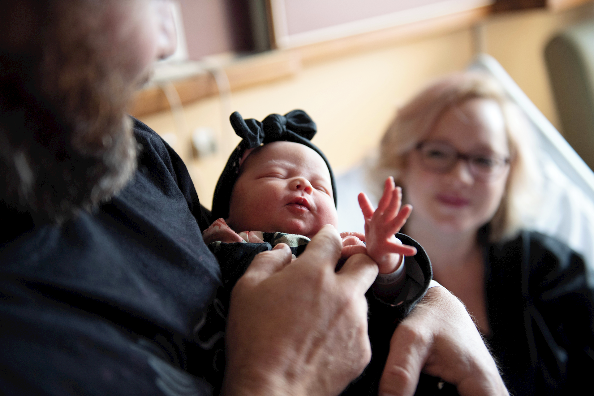 Dad holding a baby with mother in the background